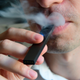 An illustration shows a man exhaling smoke from an electronic cigarette in Washington, DC on October 2, 2018.
